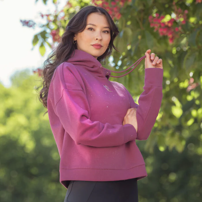 Woman wears a pink hooded top in a garden setting