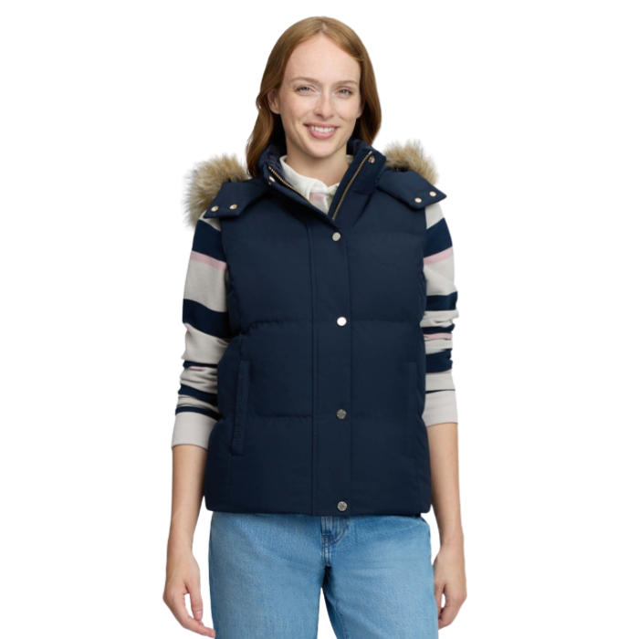 LeMieux AW26 Margot Hooded Gilet Varient Navy. Woman wearing a Navy hooded gilet with a stripy top undeneath and blue jeans on a white background.
