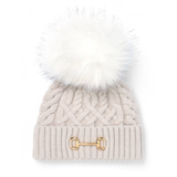 Holland Cooper Horsebit Bobble Hat Variant Taupe. A light beige cable-knit beanie with a large white faux-fur pom-pom and a gold horsebit detail on the front cuff, shown against a plain white background.
