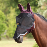Horse wearing a black and purple fly mask with a blurred green background