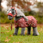 LeMieux AW26 Toy Pony Printed Turnout Rug Variant Colour Spiced Earth. A plush toy pony wearing a spiced earth colourtoy rug with star print on faded grass background.