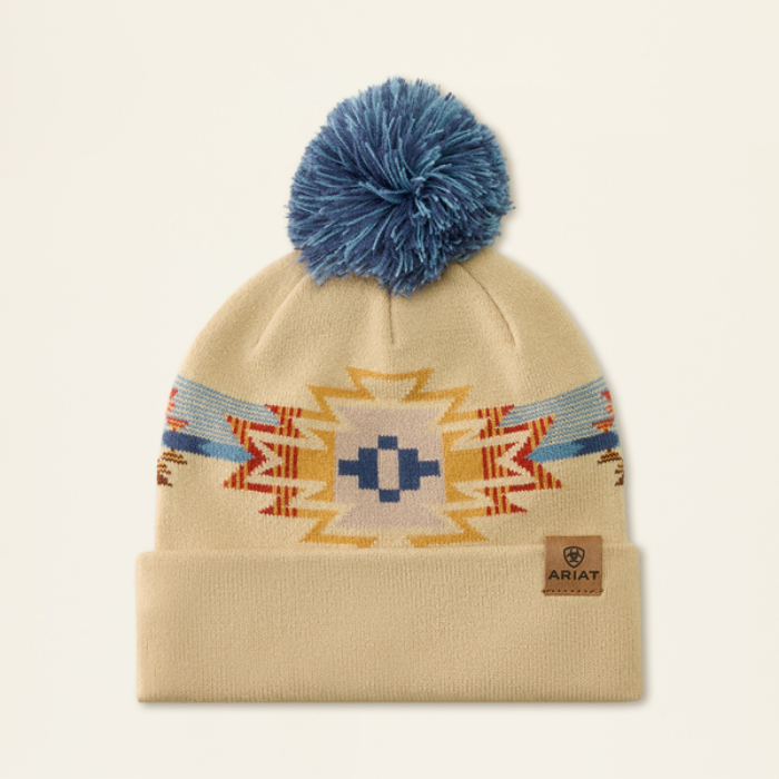 Ariat Ladies Serape Beanie Varient Natural Serape. Beige hat with a multicolour graphic, blue pom pom and a small ariat logo on a light background.