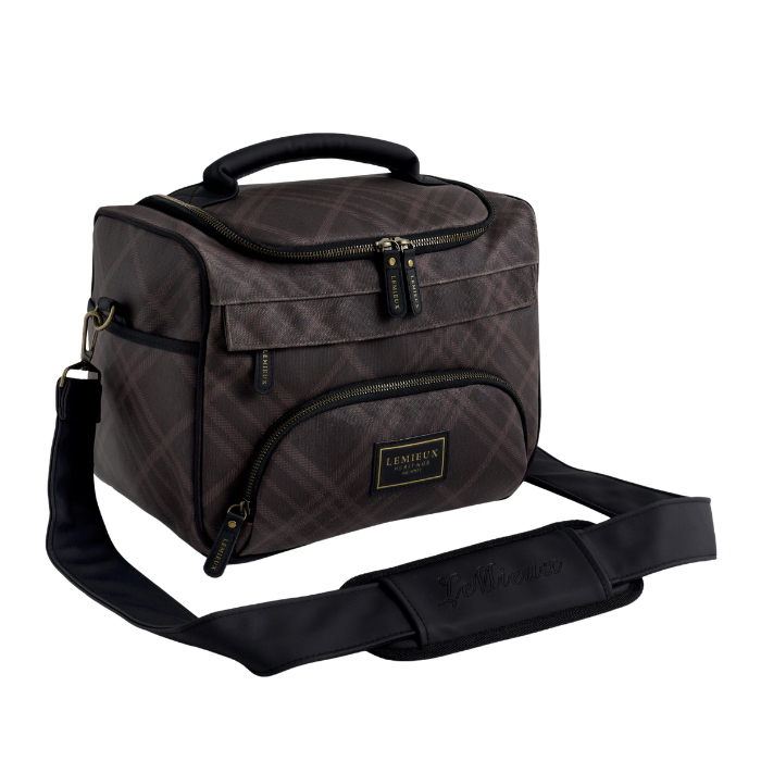 A dark brown and black plaid insulated grooming bag with a top handle, front zippered pocket, and an adjustable black shoulder strap, shown on a plain white background.