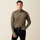 Ariat Men's Team EQ 1/2 Zip Pullover Varient Kalamanta. Man wearing a khaki long sleeve top with 1/2 zip detailing and black trousers.