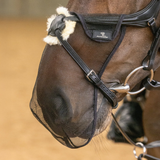 Horse wearing a black fly mask with a brand label on a blurred background