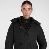 Woman wearing a black coat against a plain background