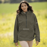 Reincoat Smock Pro Variant Olive. Lady standing in a field wearing a Olive jacket with 'REINCOAT' on the front.