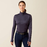 Ariat Ladies Team EQ 1/2 Zip Pullover Variant Odyssey Grey. A woman modeling a dark purple long-sleeve quarter-zip equestrian shirt paired with navy equestrian pants and a black belt with a gold buckle, against a solid light beige background.