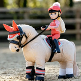 Toy horse with a rider in equestrian gear on a sandy surface