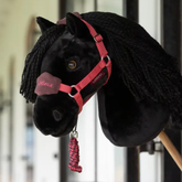 Black plush horse with a red bridle and reins on a blurred background