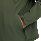 LeMieux AW26 Mens Waterproof Anorak Varient Olive. Close-up of an olive green jacket sleeve with a side pocket, showing a hand reaching into the pocket and a zipper tab near the hem.