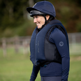 Person wearing a navy riding helmet and air jacket in an outdoor setting