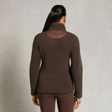 Holland Cooper Country Fleece Jacket Variant Chocolate. A woman viewed from the back wearing a dark brown long-sleeve mock neck top and matching brown leggings against a textured light gray studio background.