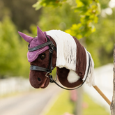 Brown and white hobby toy horse with pink hood anbd bridle on faded background