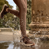 Person running through water with brown leggings and matching trainers