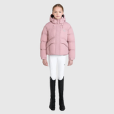 Person wearing a pink puffer jacket, white trousers, and black boots on a light grey background