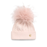 Holland Cooper Sloane Cable Bobble Hat variant Soft Pink. A light pink cable-knit beanie with a large fluffy faux-fur pom-pom on top and a small gold monogram logo on the front cuff, shown against a plain white background.