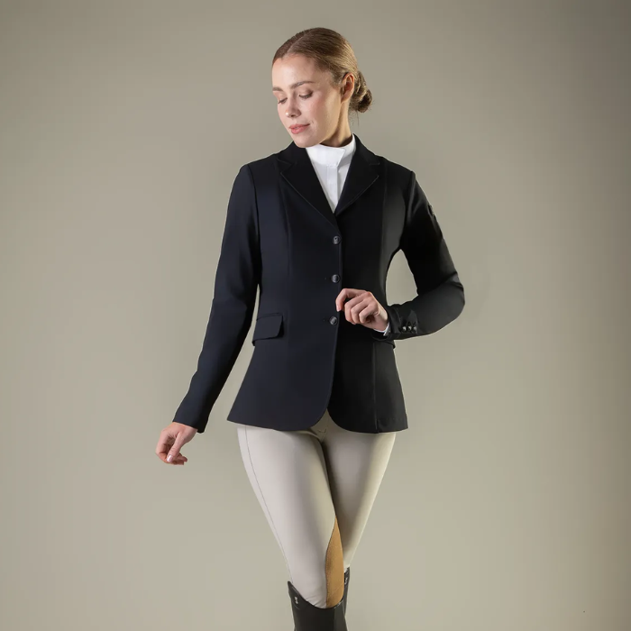 Woman wearing a black equestrian jacket on a plain background