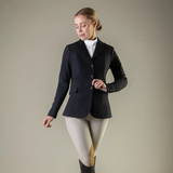 Woman wearing a black equestrian jacket on a plain background