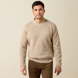Ariat Men's Heddon Sweater Varient Oatmeal Heather. Man wearing a beige coloured wool jumper and brown trousers on a beige background.