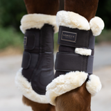 LeMieux AW26 Heritage Fleece Edged Brushing Boot Varient Cocoa. Close-up of a horse's lower legs wearing brown protective boots with thick cream-colored fleece lining. A brand label reading 'LeMieux Heritage' is visible on the front boot.