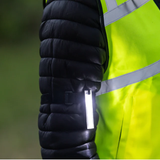 Close-up of a black puffer jacket with reflective striping on a green background