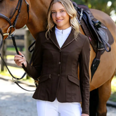 Woman in a brown equestrian jacket standing next to a horse