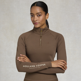 Woman wearing a brown equestrian top with 'Holland Cooper' branding on a neutral background