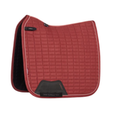 LeMieux AW26 Suede Dressage Square Varient Russet. A red quilted equestrian saddle pad with black trim and black interior lining, featuring a grid pattern and a black leather patch at the front, shown on a white background.