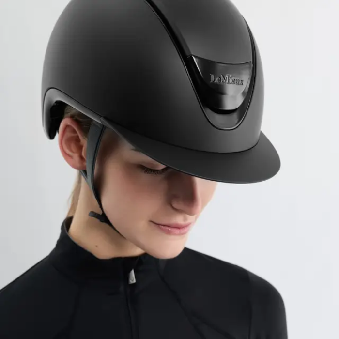 Person wearing a black riding helmet with 'Le N髆eux' branding on a light gray background