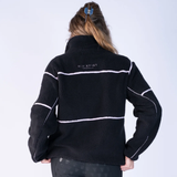 Blackfort AW26 Layla Fleece Variant Black & Blush. A person viewed from the back wearing a black fleece pullover jacket with white contrast stitching and a small white 'BLACKFORT' logo on the upper back, against a light gray studio background.