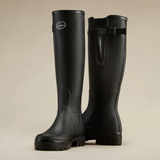 Pair of black rubber boots with a buckle on a beige background