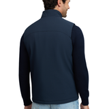 LeMieux AW26 Mens Midweight Insulated Gilet Varient Navy. A man shown from the back wearing a navy blue quarter-zip fleece jacket with solid navy sleeves, paired with light blue jeans, against a plain white background.