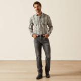 Man wearing a plaid shirt, dark jeans, and black shoes on a plain background
