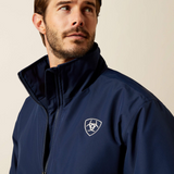 Man wearing a navy blue jacket with a logo on a beige background