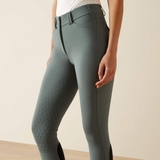 Green riding pants worn by a person on a beige background