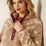 Woman wearing a beige fleece jacket with a maroon zipper against a neutral background
