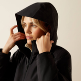 Person wearing a black hooded jacket against a beige background