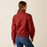 Person wearing a brown jacket and blue jeans on a beige background