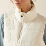 Close-up of a person wearing a cream-colored puffer vest.