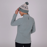 Person wearing a light blue fleece jacket and matching beanie on a plain background