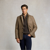 Holland Cooper Classic Quarter Zip Sweat (Men's) Variant Colour Bournville. A male model wearing a brown jacket, grey coloured sweater and blue jeans on grey background.