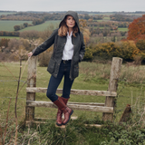 Woman standing on a wooden stile in a countryside setting