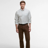 Man wearing a checked shirt and brown trousers on a light grey background