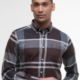 Man wearing a tartan shirt with a visible brand logo on a plain background
