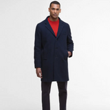 Man wearing a navy wool coat over a red sweater on a white background