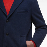 Navy blue wool coat with red sweater underneath on a white background