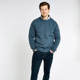 Man wears a blue knitted jumper over a collared shirt on a white background