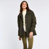 Woman wears a cream knit with a green waxed jacket and olive trousers on a white background