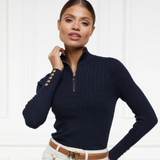 Woman wearing a navy blue ribbed jumper with gold buttons on a white background